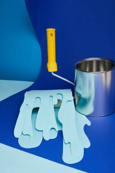 Metal shiny can near roller with dripping paper cut paint on bright blue background — Stock Photo