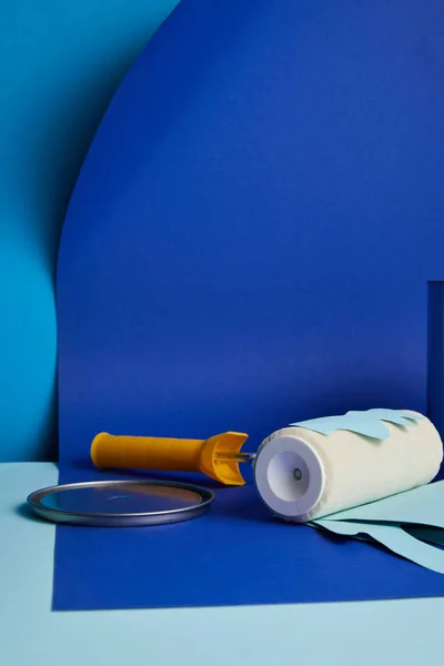 Metal cap near roller with dripping paper cut paint on bright blue background — Stock Photo