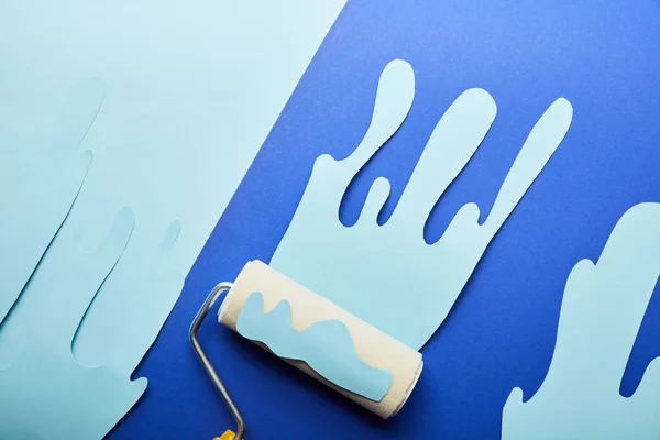 Draufsicht der Walze mit blauem Papierschnitt tropfende Farbe auf hellem Hintergrund — Stockfoto
