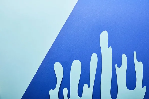 Top view of blue paper cut dripping paint on bright blue background — Stock Photo