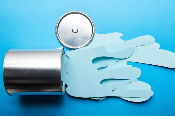 Top view of spilled paper cut blue paint near silver can and cap — Stock Photo