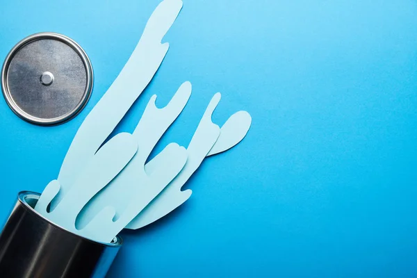 Top view of spilled paper cut blue paint near metal can and cap — Stock Photo