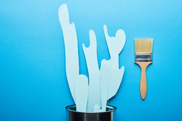 Top view of spilled paper cut blue paint from silver can near brush — Stock Photo