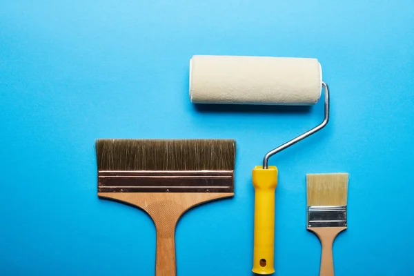 Top view of roller and brushes on blue bright background with copy space — Stock Photo