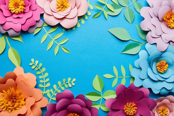 Vista superior de flores de corte de papel multicoloridas com folhas no fundo azul com espaço de cópia — Fotografia de Stock