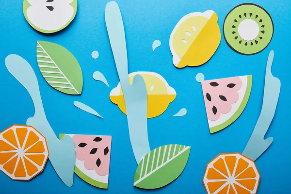 Top view of paper cut water splashes with fruits on blue background — Stock Photo