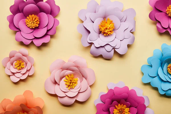 Vista superior de coloridas flores cortadas en papel sobre fondo beige - foto de stock