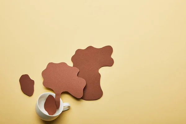 Top view of paper cut coffee spills near cup on beige background — Stock Photo