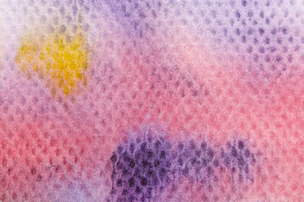 Vista de cerca de los derrames de pintura de acuarela amarilla y púrpura sobre fondo texturizado - foto de stock