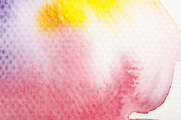 Вид зверху на жовтий, фіолетовий і червоний акварельні бліді фарби розливаються на білому тлі — стокове фото