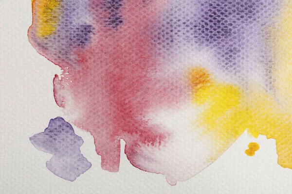 Top view of yellow, purple and red watercolor paint spills on paper background — Stock Photo