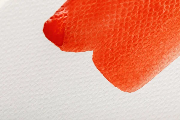 Vue rapprochée de peinture aquarelle rouge coup de pinceau humide sur fond texturé blanc — Photo de stock