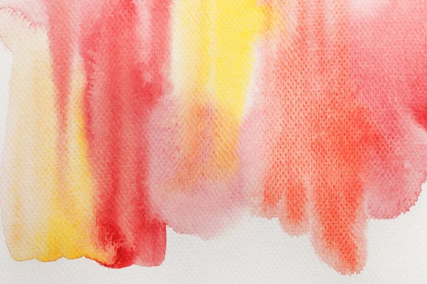 Vue rapprochée des déversements de peinture aquarelle jaune pâle et rouge sur fond blanc — Photo de stock