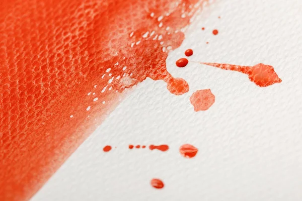 Vista de cerca de la pincelada de pintura de acuarela roja con gotas sobre fondo texturizado blanco - foto de stock