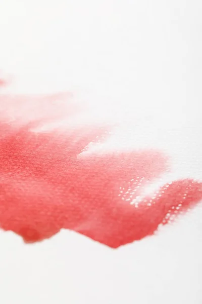 Vue rapprochée du déversement de peinture aquarelle rouge humide sur fond blanc — Photo de stock