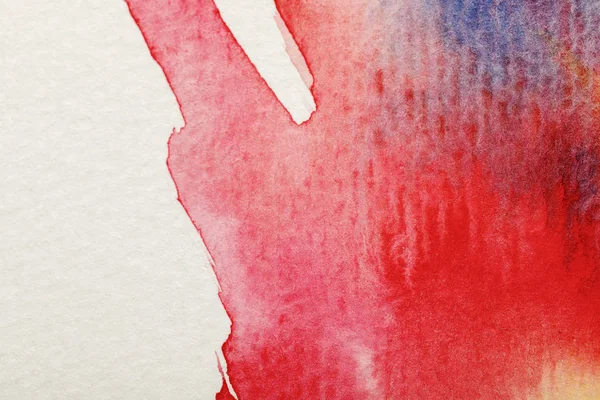 Vue rapprochée des déversements mixtes de peinture aquarelle bleu vif et rouge sur fond blanc — Photo de stock