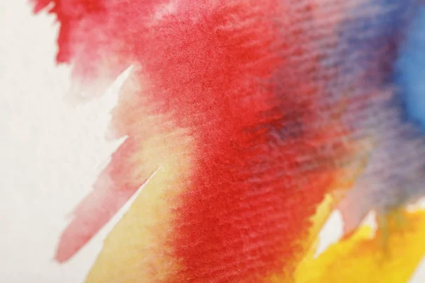 Close up view of multicolored watercolor paint spills on white background — Stock Photo