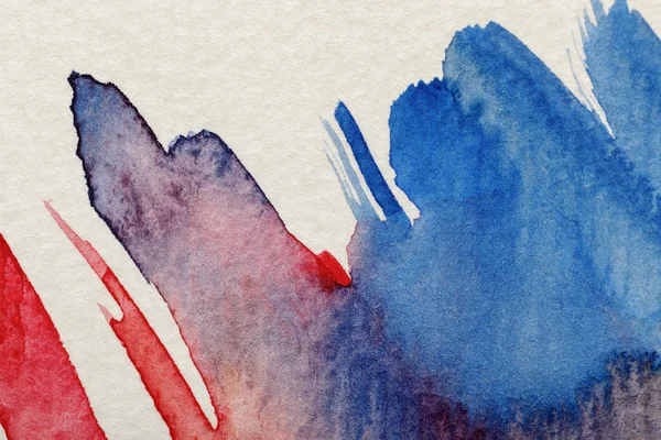 Vue rapprochée des coups de pinceau aquarelle bleu et rouge sur fond texturé blanc — Photo de stock