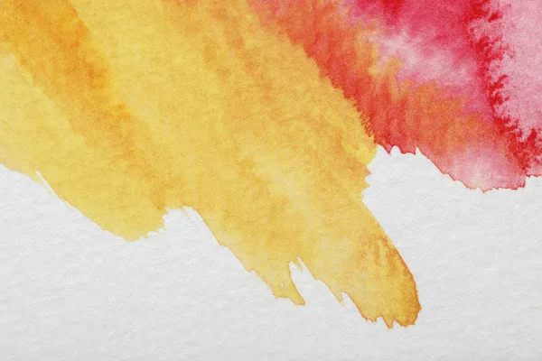 Close up view of yellow and red mixed watercolor paint spills on white background — Stock Photo