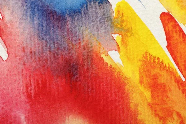 Vista de cerca de amarillo húmedo, azul y rojo acuarela pinceladas de pintura sobre fondo blanco - foto de stock