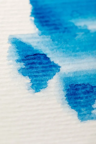 Vista de cerca de los derrames de pintura de acuarela azul sobre fondo de papel texturizado - foto de stock