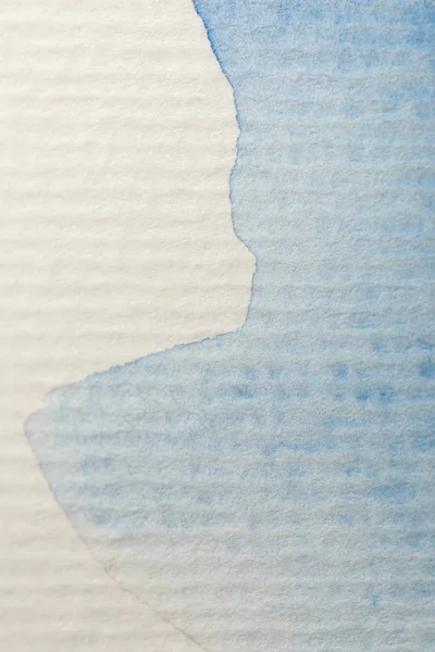 Vista de cerca del derrame de pintura de acuarela azul sobre fondo de papel texturizado con espacio de copia - foto de stock