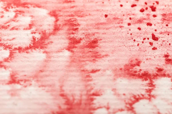 Vista de cerca del derrame de pintura de acuarela colorida roja sobre fondo de papel texturizado - foto de stock