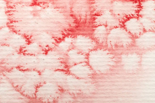 Close up view of red watercolor paint spill on textured paper background — Stock Photo