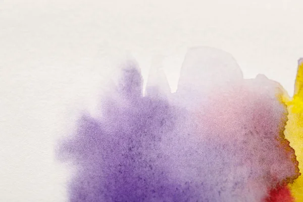 Close up view of yellow, purple and red watercolor paint spills on white background — Stock Photo