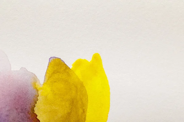 Close up view of yellow and purple watercolor paint spills on white background — Stock Photo