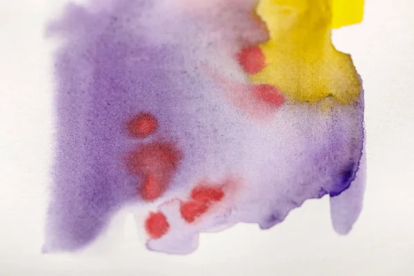 Vista de cerca de los derrames de pintura de acuarela de color amarillo brillante, púrpura y rojo - foto de stock