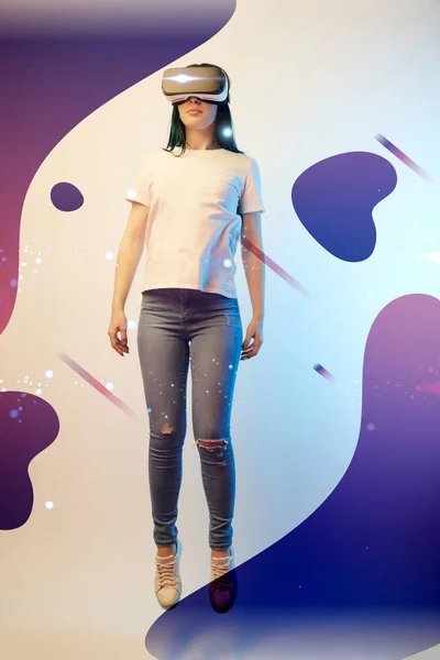 Young woman in virtual reality headset levitating in air among glowing and abstract purple illustration on beige background — Stock Photo