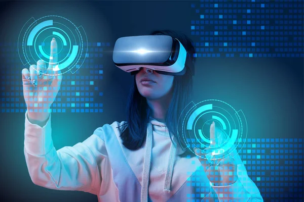Junge Frau im vr-Headset zeigt mit den Fingern auf glühende Cyber-Illustration auf dunklem Hintergrund — Stockfoto