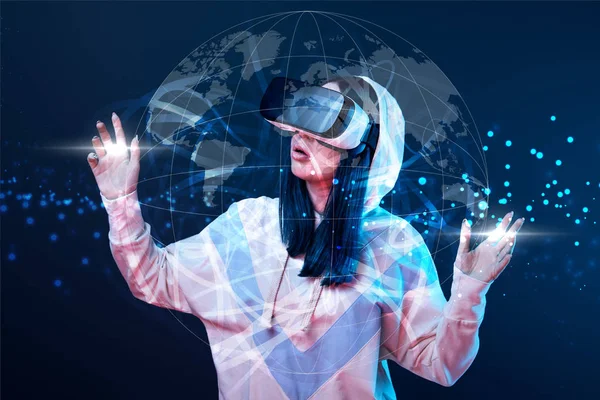 Shocked young woman in vr headset gesturing near glowing globe illustration on dark background — Stock Photo