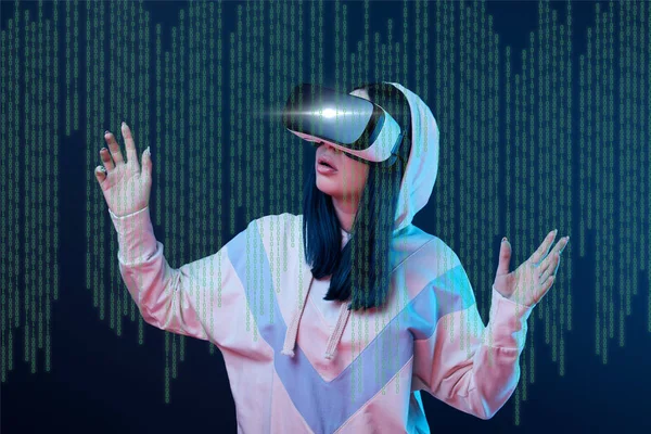 Excited young woman in vr headset gesturing near data illustration on dark background — Stock Photo