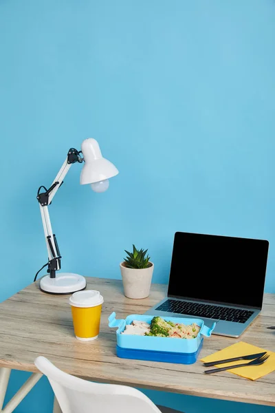 Healthy food in blue lunch box on wooden table on blue background, illustrative editorial — Stock Photo