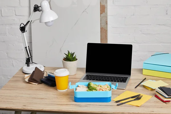 Lunch box with rice, chicken and broccoli at workplace with laptop on wooden table on white background, illustrative editorial — Stock Photo