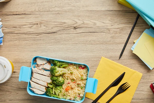 Vista superior de la lonchera de plástico con arroz, brócoli y pollo sobre mesa de madera - foto de stock