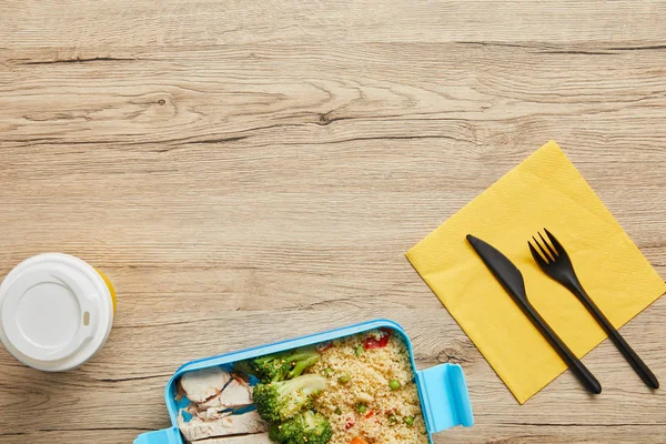 Vista superior de café para llevar y lonchera de plástico con risotto, brócoli y pollo sobre mesa de madera — Stock Photo