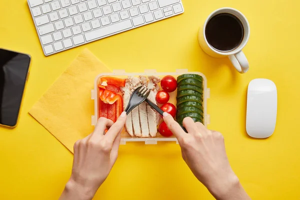 Vista cortada da mulher comendo almoço saudável e saboroso no local de trabalho no fundo amarelo — Stock Photo
