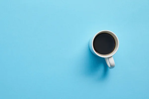 Draufsicht auf Tasse heißen Kaffee auf blauem Hintergrund — Stockfoto