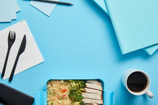 Vue du dessus de la boîte à lunch avec riz, poulet et brocoli au travail sur fond bleu — Photo de stock