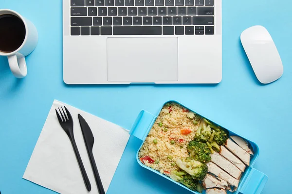 Vista superior de dispositivos digitais, xícara de café e lancheira com frango saboroso, arroz e brócolis em fundo azul, editorial ilustrativo — Stock Photo