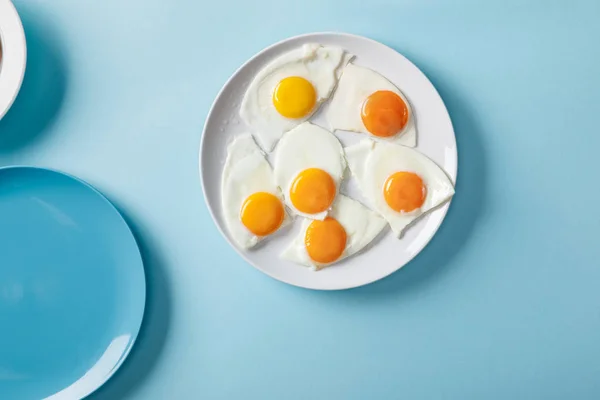 Top view of fried eggs on white plate on blue background — Stock Photo