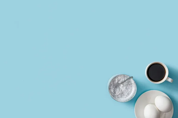 Vista superior de ovos frescos na placa branca, iogurte com sementes de chia e café — Fotografia de Stock