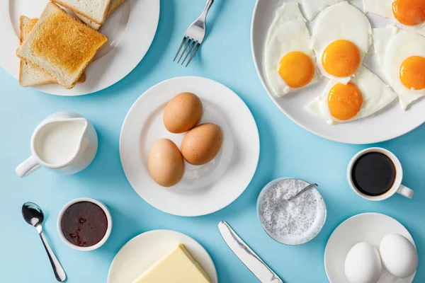 Draufsicht auf das servierte Frühstück mit gekochten und gebratenen Eiern auf blauem Hintergrund — Stockfoto