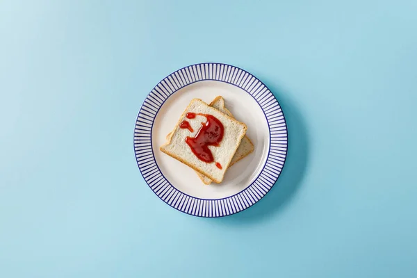 Vue de dessus des toasts avec confiture sur plaque sur fond bleu — Photo de stock