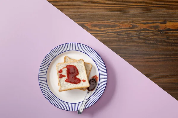 Draufsicht auf Toasts, Löffel mit Marmelade auf violettem und hölzernem Hintergrund — Stockfoto