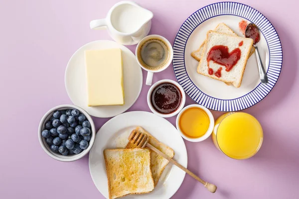 Draufsicht auf das servierte Frühstück mit Tasse Kaffee und Orangensaft auf violettem Hintergrund — Stockfoto