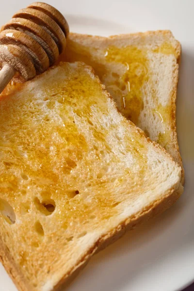 Vista de cerca de los brindis con miel y cazo de madera en plato blanco - foto de stock